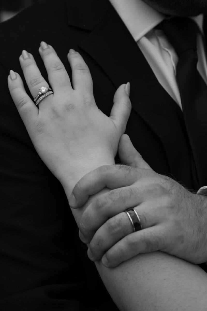 A couple’s wedding rings in a black-and-white portrait